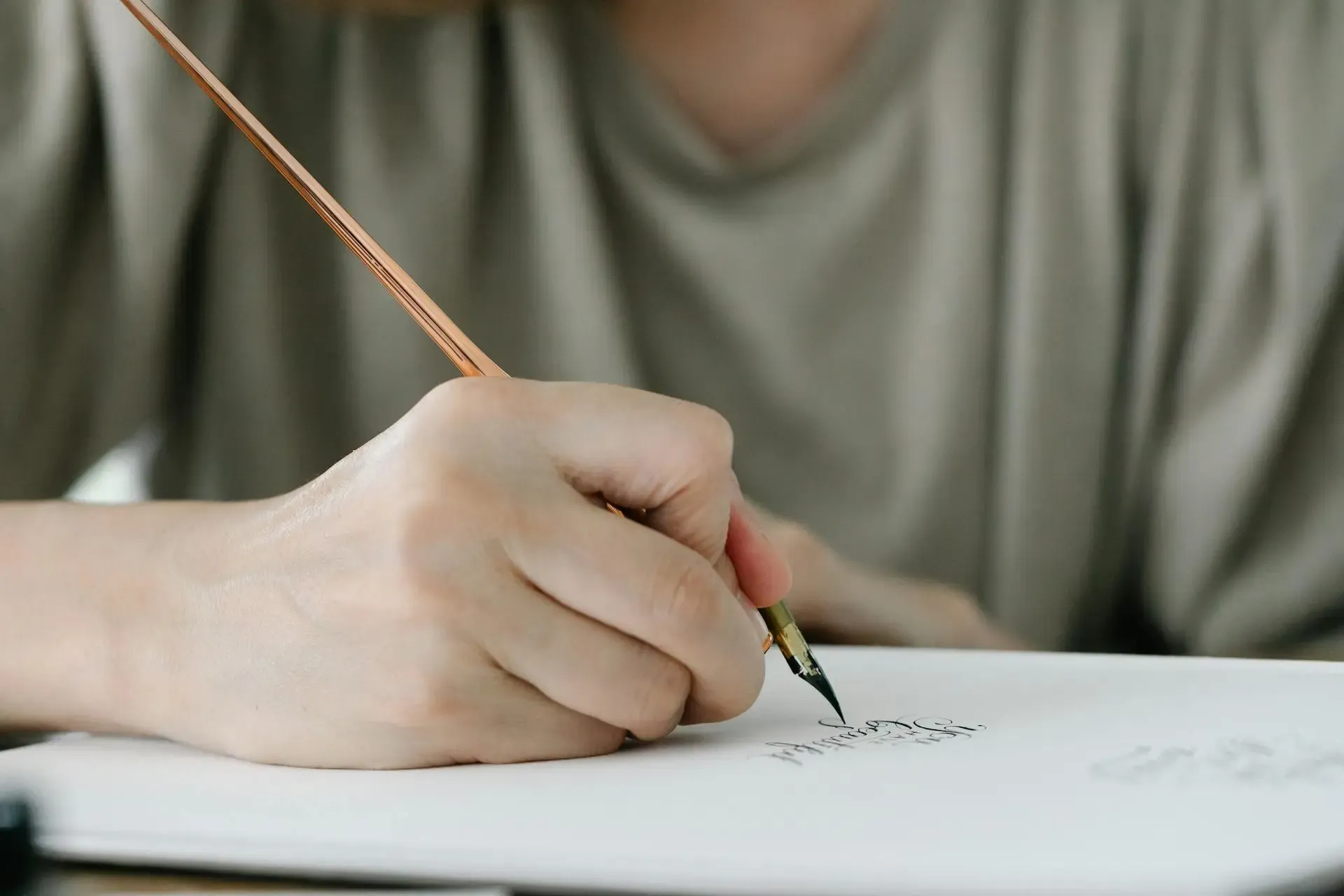 A close-up shot of a person writing calligraphy on a piece of paper